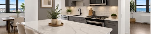 A modern kitchen with a marble countertop and white chairs.