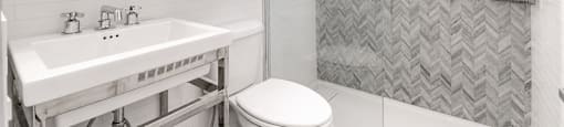 A bathroom with a toilet, sink, and shower.