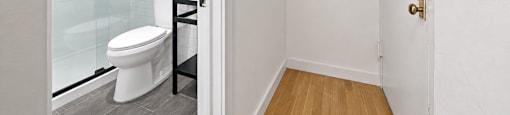 A white toilet is in a small bathroom with a glass door.