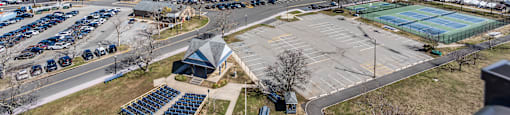 A parking lot with a tennis court and a marina in the background.
