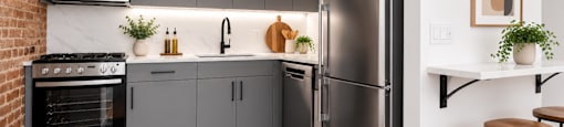 A modern kitchen with a stainless steel refrigerator and a brick wall.