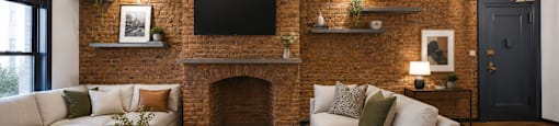 A living room with a brick wall and a fireplace.