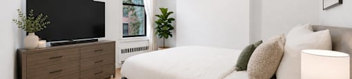 A bedroom with a bed, a dresser, and a window.
