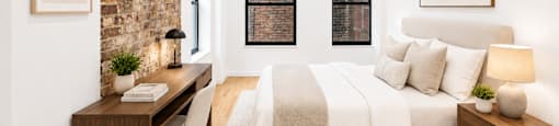 A bedroom with a large bed and a desk with a chair.