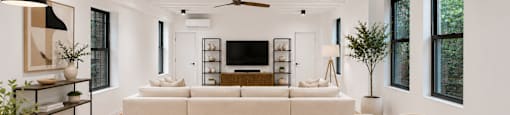 A modern living room with a white sofa set and a wooden dining table.
