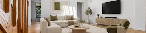 A living room with a staircase on the left and a couch and coffee table in the center.