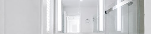 A white bathroom with a toilet, sink, and shower.