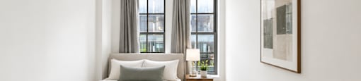 A bedroom with a bed, nightstand, and a window with curtains.