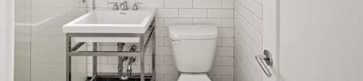 A white bathroom with a toilet, sink and mirror.
