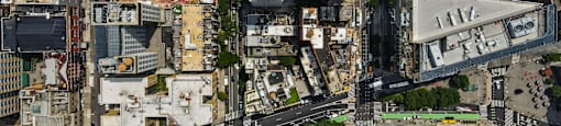 A bird's eye view of a city with buildings, roads, and green spaces.
