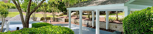 a pavilion with a seating area and a swimming pool in the background