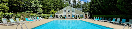 a swimming pool with chaise lounge chairs and a house in the background