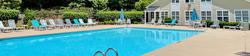 a swimming pool with lounge chairs and a house in the background