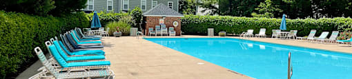 a swimming pool with chaise lounge chairs and trees in the background