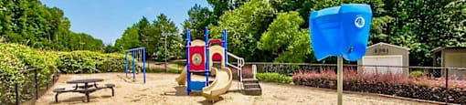 a playground with a playground equipment and picnic table in a park