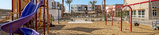 A playground with a purple slide and red swings.