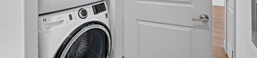 A white door is open to a laundry room with a washer and dryer.