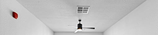 A room with a ceiling fan and a window with blinds.