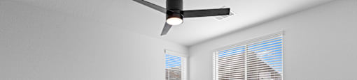 A room with a ceiling fan and carpeted floor.
