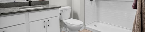 A white bathroom with a toilet, sink, and shower.