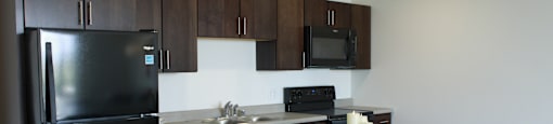 a kitchen with a black refrigerator freezer next to a stove top oven