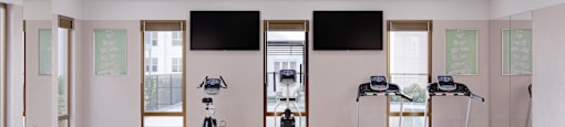 a gym with treadmills and flat screen televisions