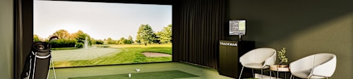 a room with a golf simulator and a view of a putting green
