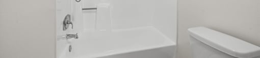 A white bathroom with a glass shower door and a white tub and toilet.