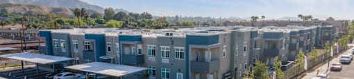 a row of apartment buildings with cars parked in front of them at Loma Villas Apartments, San Bernardino California