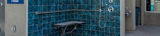a blue tiled shower stall in a public restroom at Loma Villas Apartments, California, 92408