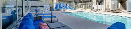 a pool area with blue couches and umbrellas at Loma Villas Apartments, California, 92408