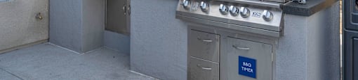 an outdoor kitchen with a grill and sink at Loma Villas Apartments, California, 92408