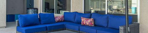 a patio with a blue sectional sofa and gray wicker chairs at Loma Villas Apartments, California