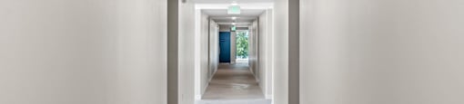 a long corridor with white walls and beige carpet at Loma Villas Apartments, San Bernardino California