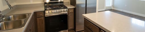 a kitchen with wooden cabinets and stainless steel appliances at Loma Villas Apartments, San Bernardino, California