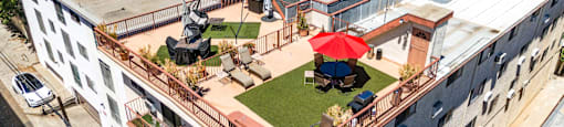 Rooftop patio with dining area and red umbrella at Joro Properties Apartments, Hollywood, 90046