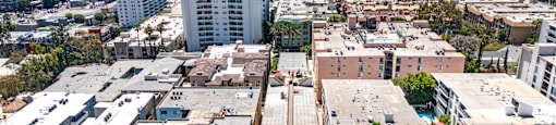 Aerial view of apartment buildings and lush trees at Joro Properties Apartments, California, 90046