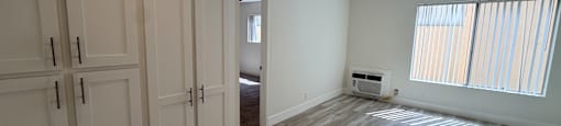 A room with wooden flooring and white cabinets.