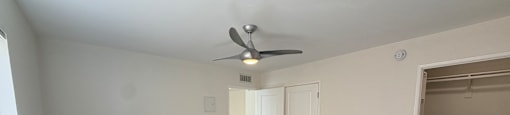 A room with a ceiling fan and carpeted floor.