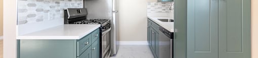 Galley kitchen with sage cabinets and white countertops at Joro Properties Apartments, Hollywood, CA 90046