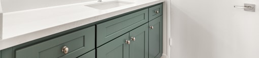 Bathroom vanity with green cabinets and backlit mirror at Joro Properties Apartments, Hollywood, CA 90046