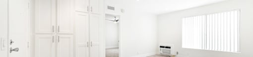 Empty room with white vertical blinds and light wood flooring at Joro Properties Apartments, Hollywood, 90046