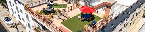 Rooftop terrace with red umbrella and artificial grass at Joro Properties Apartments, California, 90046
