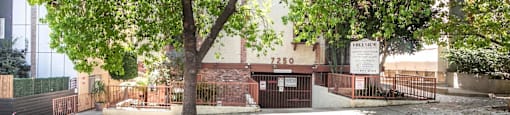 Property entrance with large tree and fenced parking area at Joro Properties Apartments, Hollywood