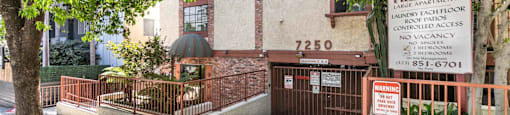Apartment entrance with property sign and gated access at Joro Properties Apartments, California