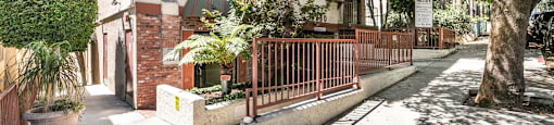 Tree lined walkway with residential building and fencing at Joro Properties Apartments, California, 90046