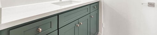 Bathroom vanity with sage green cabinetry and white countertop at Joro Properties Apartments, Hollywood