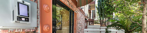 Brick building entrance with intercom and striped awning at Joro Properties Apartments, Hollywood, 90046