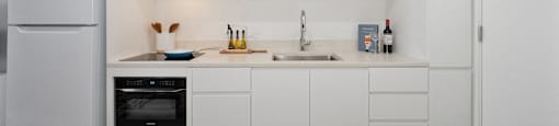 a kitchen with white cabinets and a sink and a refrigerator