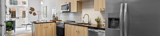 A kitchen with wooden cabinets and stainless steel appliances at BridgeWay Station new apartments in Simpsonville, SC